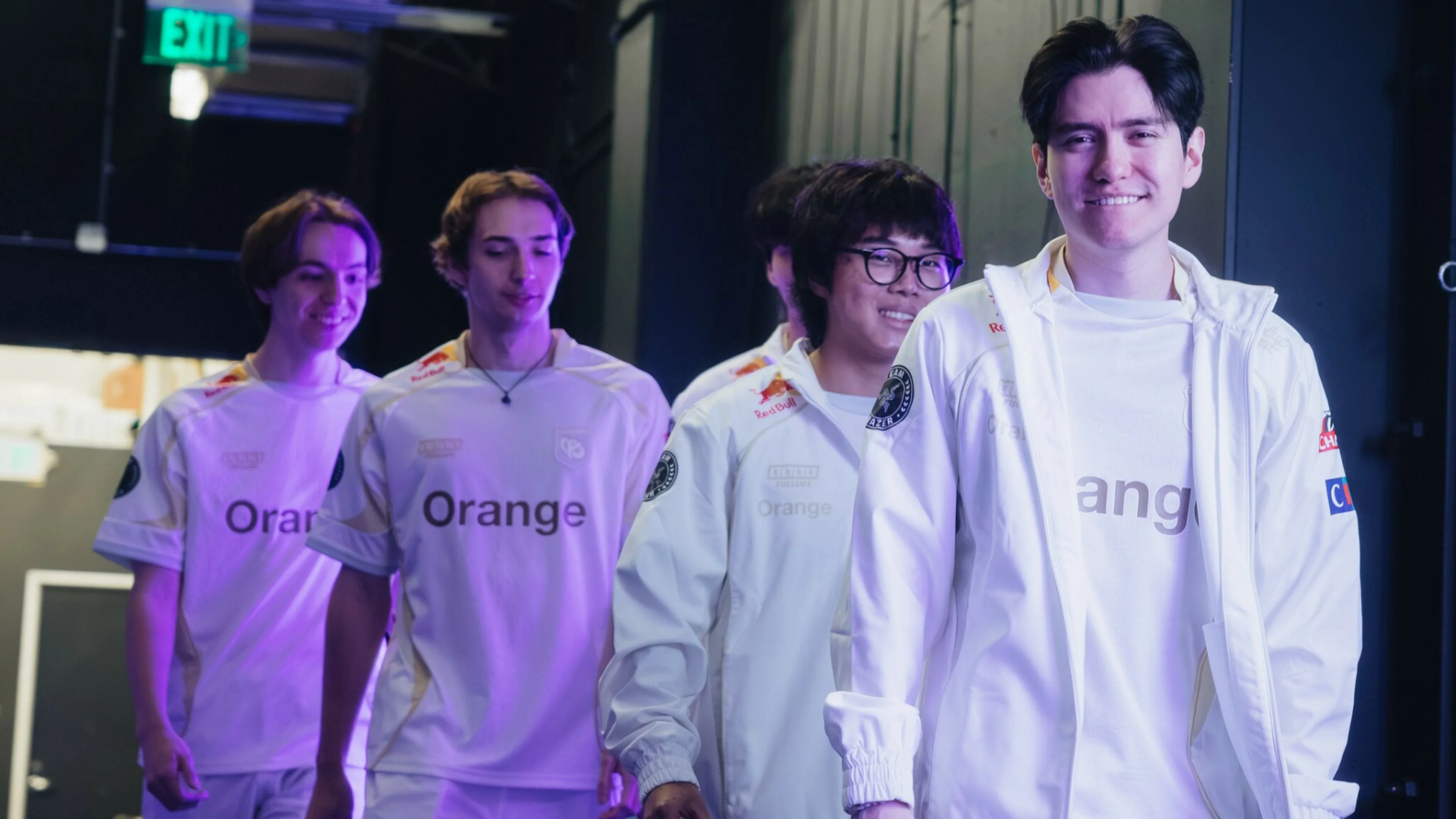 Four Karmine Corp League of Legends players wearing white team jerseys walk together backstage at an esports event.