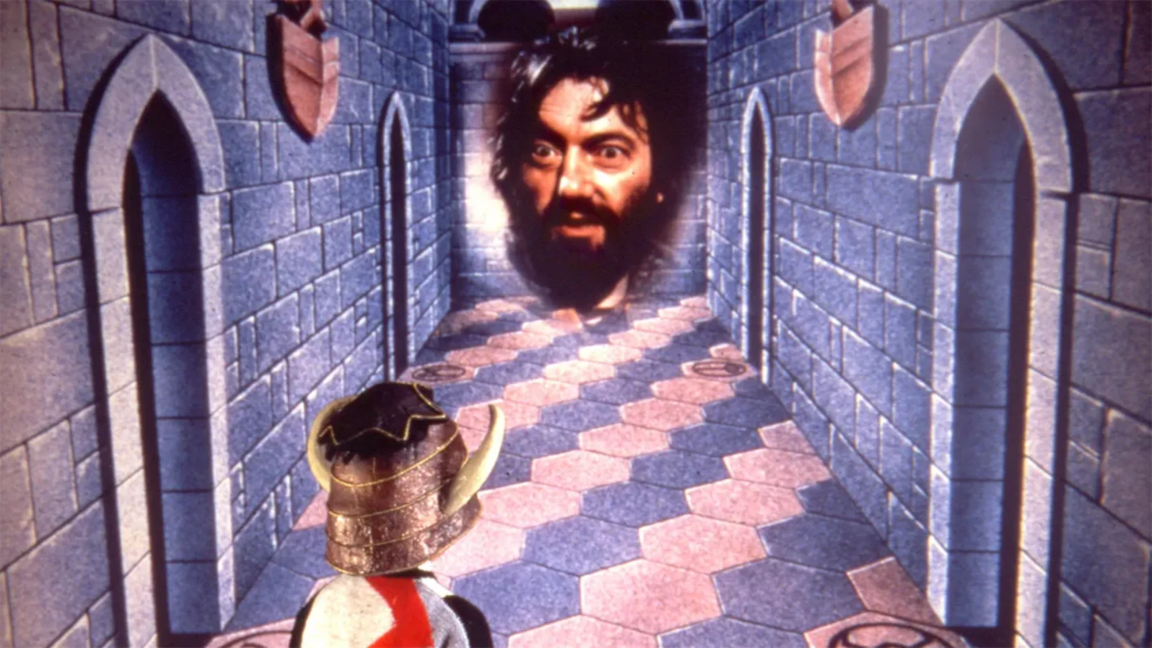 Knightmare television show scene featuring a helmeted Dungeoneer inside a medieval stone corridor facing a giant floating, bearded head.