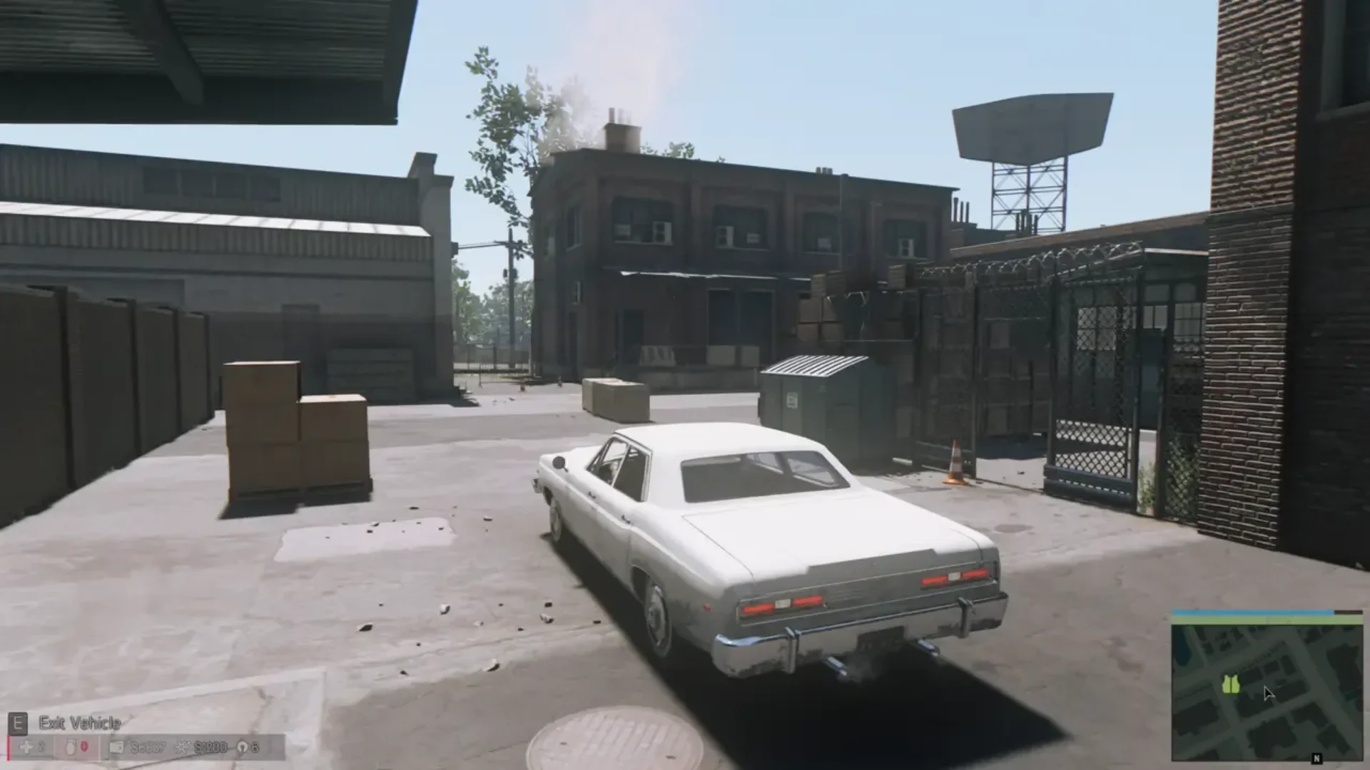 Mafia III: Definitive Edition gameplay showing a white sedan in an industrial area with brick buildings and fenced warehouses.