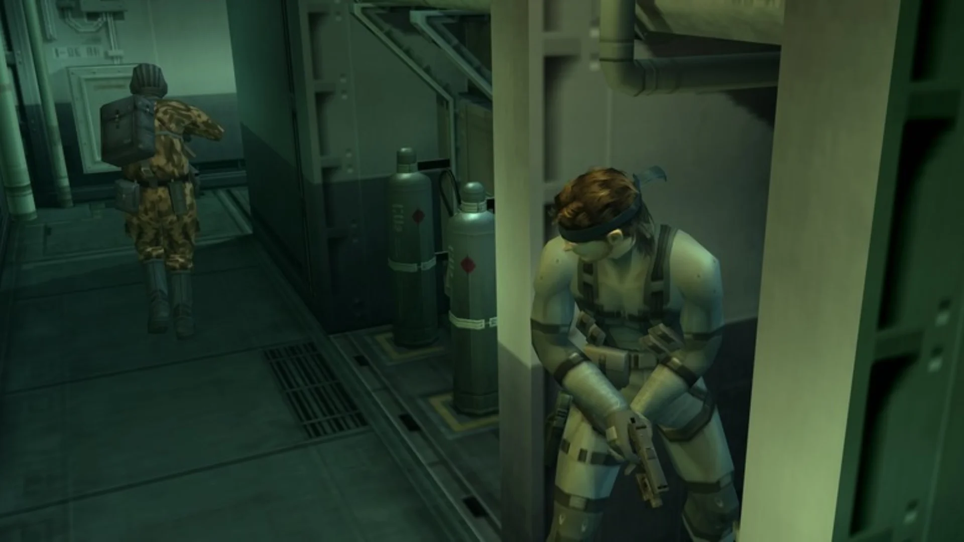 Snake hides beside a wall as a guard walks through an industrial corridor in Metal Gear Solid 2.