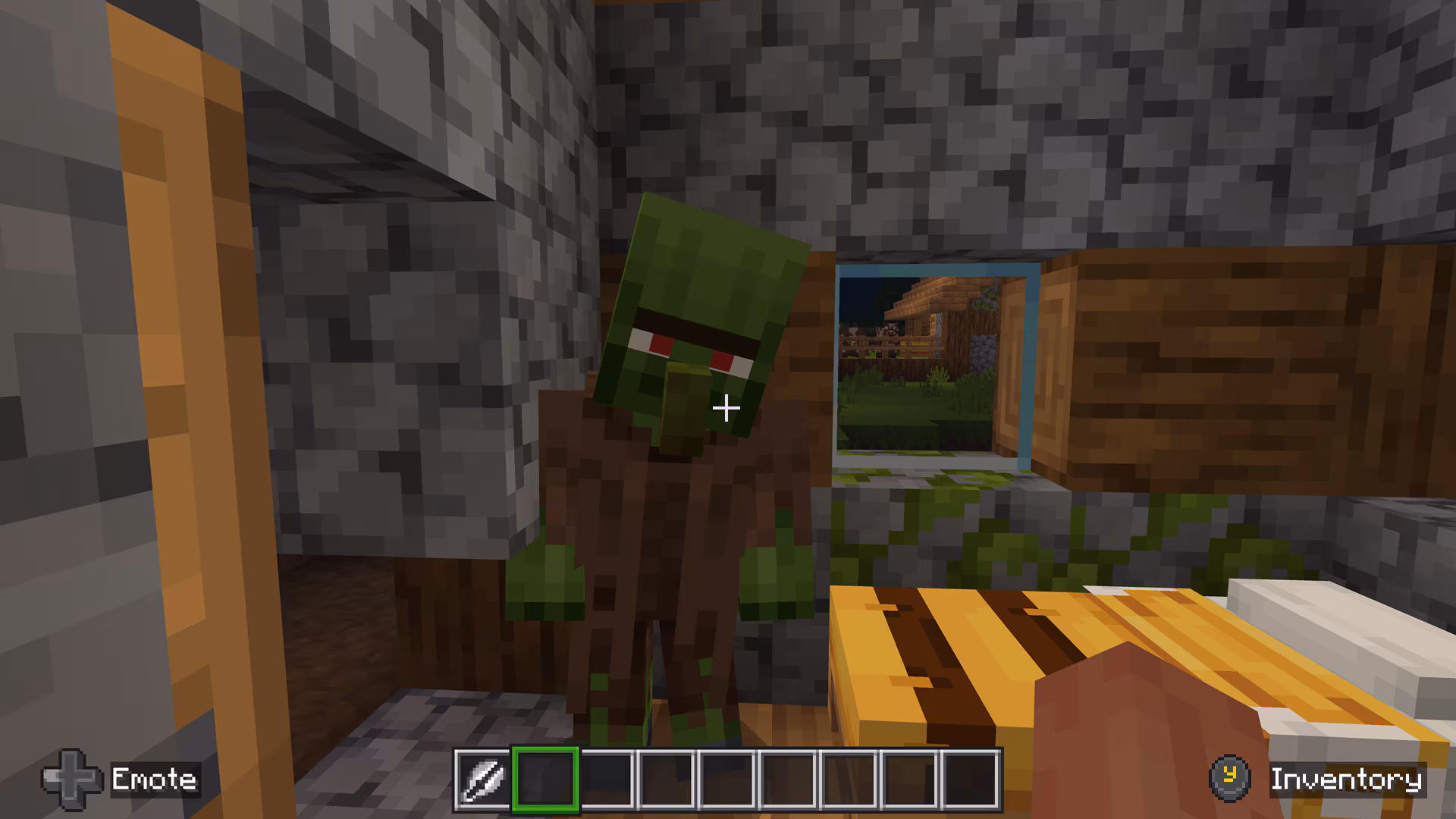 A zombie villager tilts its head inside a house in Minecraft Bedrock with Actions & Stuff enabled.