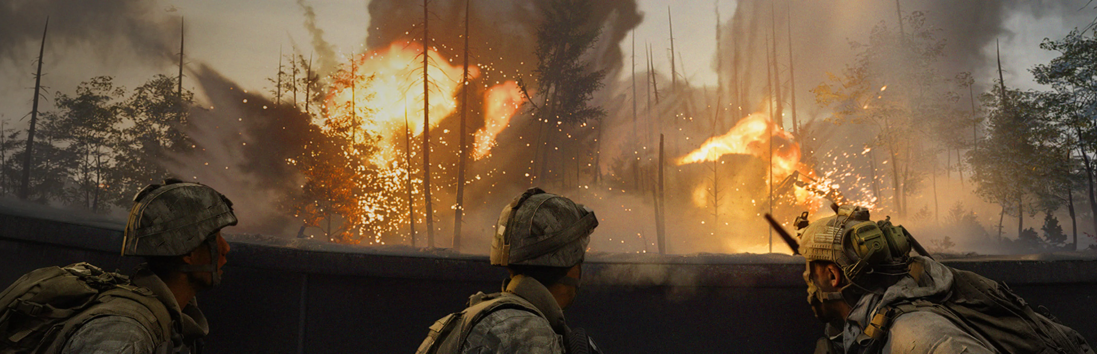 Three soldiers wearing military helmets and tactical gear take cover behind a concrete barrier as explosions engulf a forest.