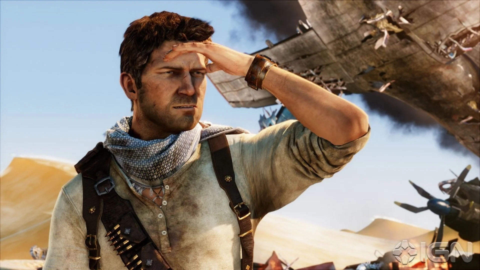 Nathan Drake shields his eyes from the sun beside wreckage in the desert in Uncharted 3: Drake's Deception.