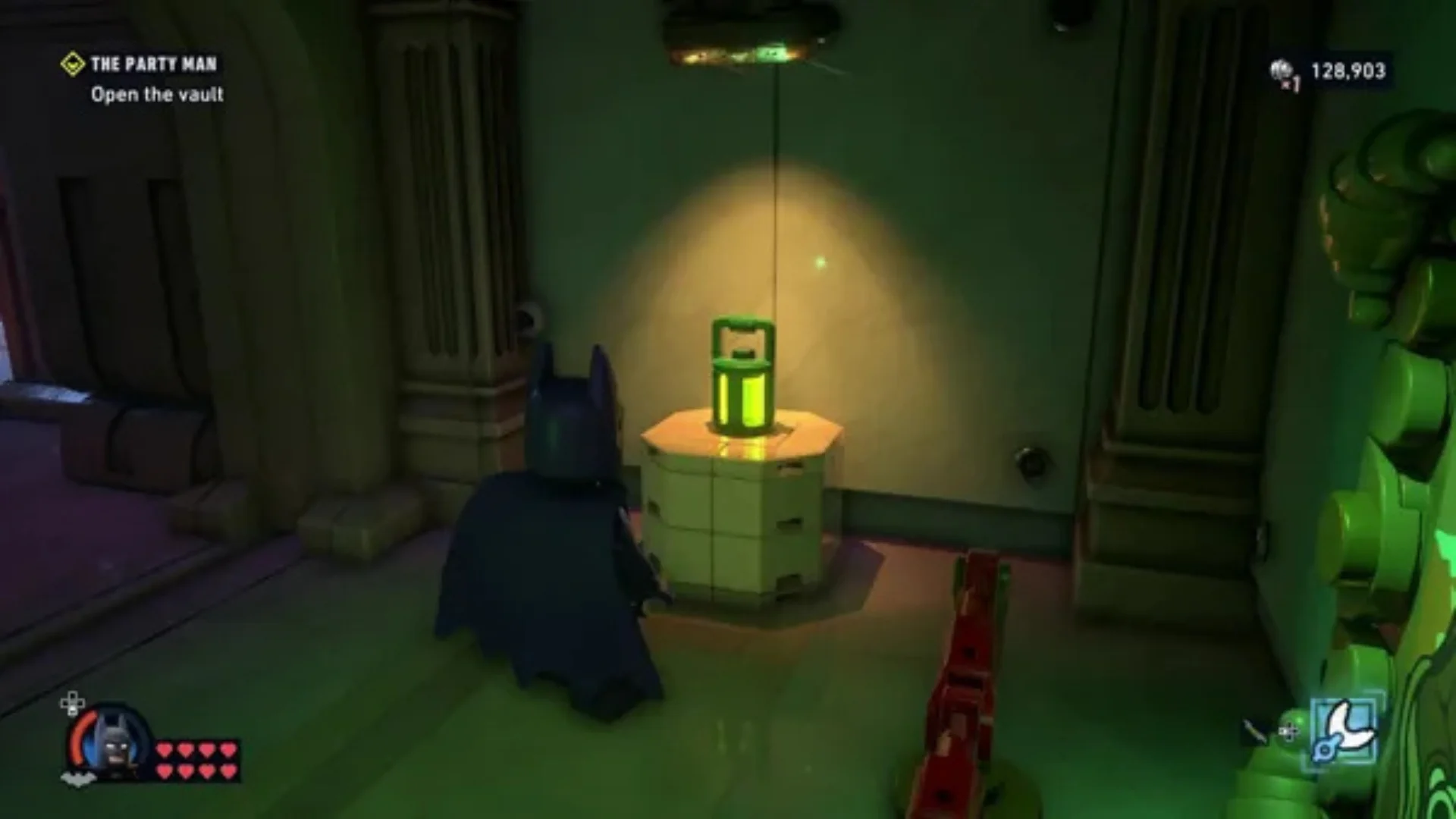 LEGO Batman approaches a glowing green object inside a dark vault during gameplay.
