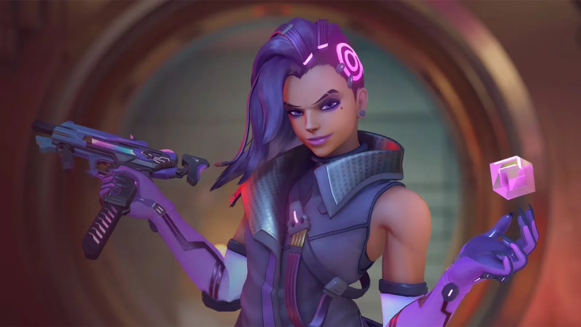 Sombra holds her weapon and a glowing cube after moving to the Support role in Overwatch.