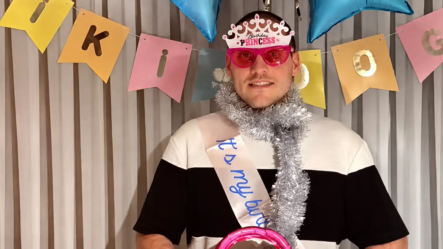 RRaenee wearing pink glasses, a birthday princess tiara and silver tinsel during a livestream.
