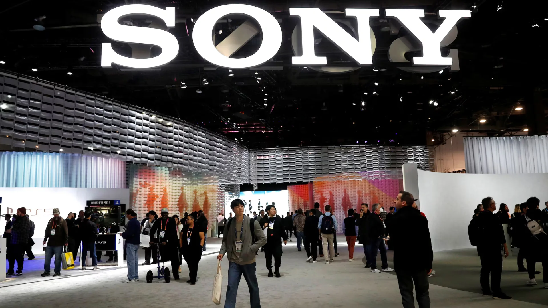 Visitors walk through a Sony exhibition booth beneath a large illuminated SONY sign at CES.