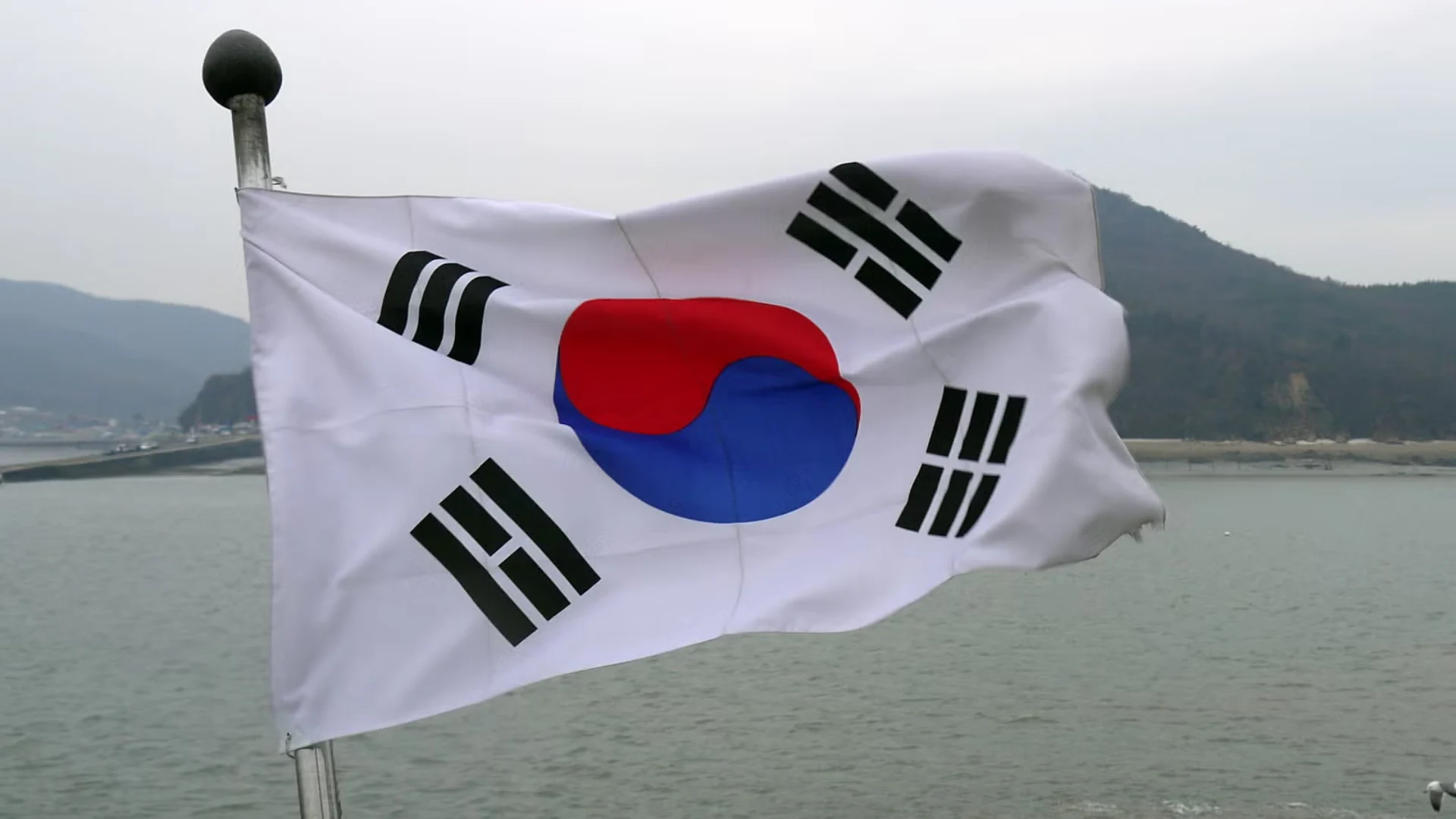 South Korean national flag flying outdoors with mountains in the background