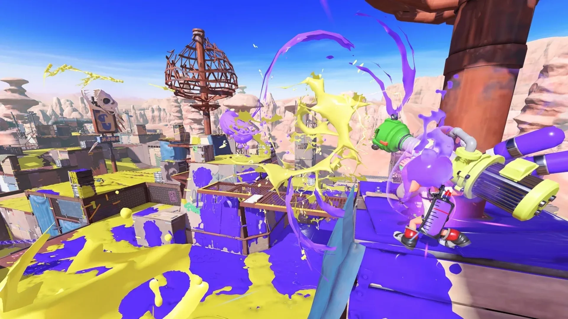 An Inkling fires purple ink across a multiplayer stage covered in yellow and purple ink.
