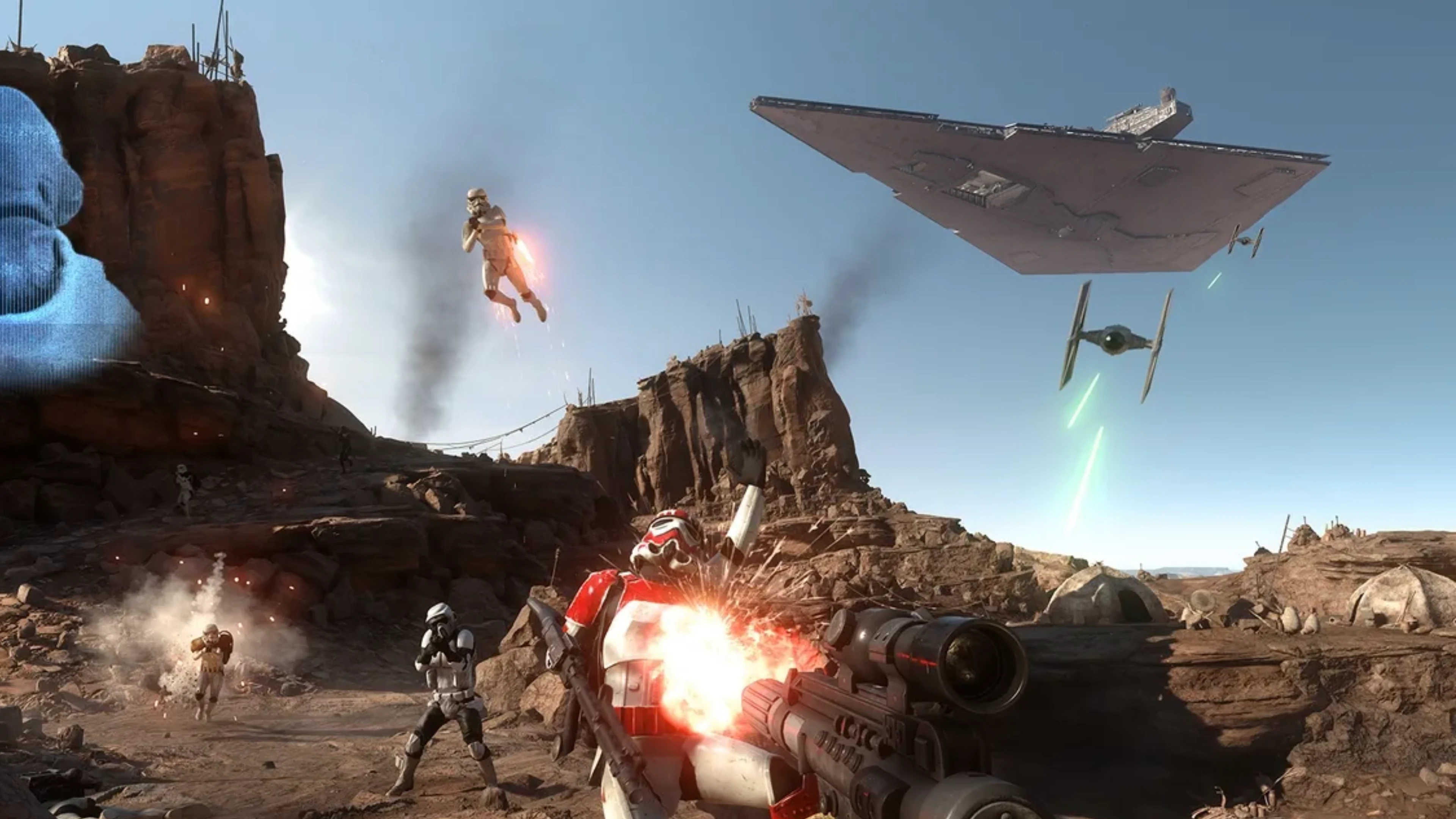 Star Wars Battlefront II gameplay showing two Rebel soldiers activating a glowing blue device in a forest while an Imperial AT-ST approaches.