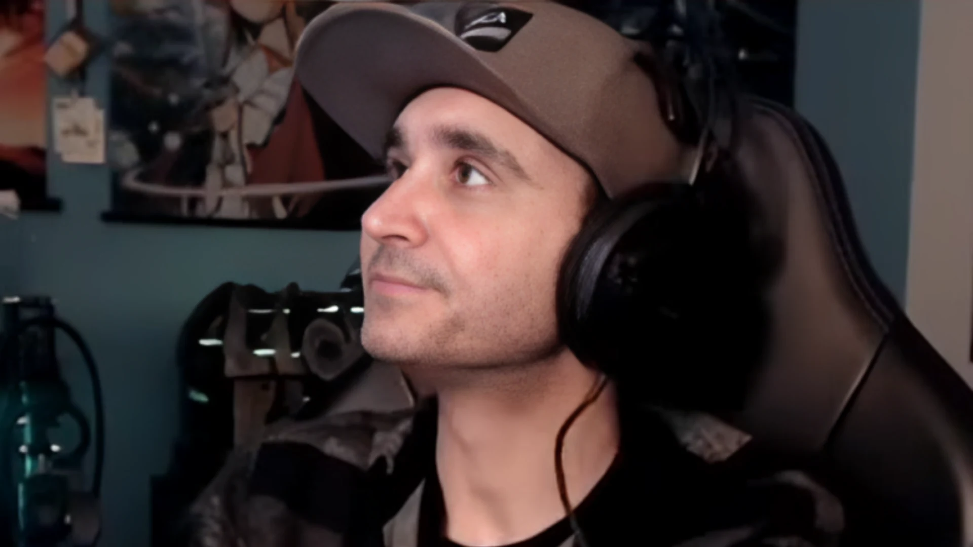 Gaming streamer wearing a cap and headset while seated at a computer setup