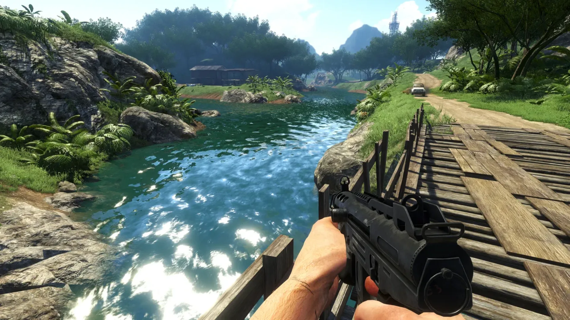 First-person view of a weapon overlooking a tropical river and dirt road in Far Cry 3.
