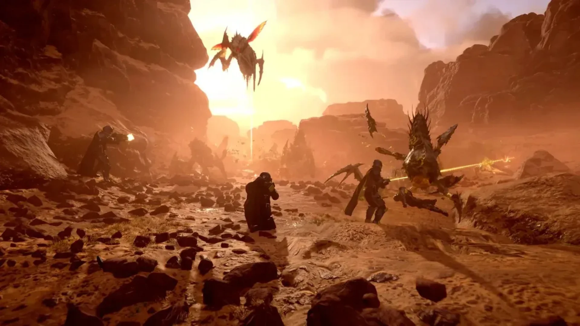 Helldivers battle Terminid creatures across a rocky battlefield in Helldivers 2