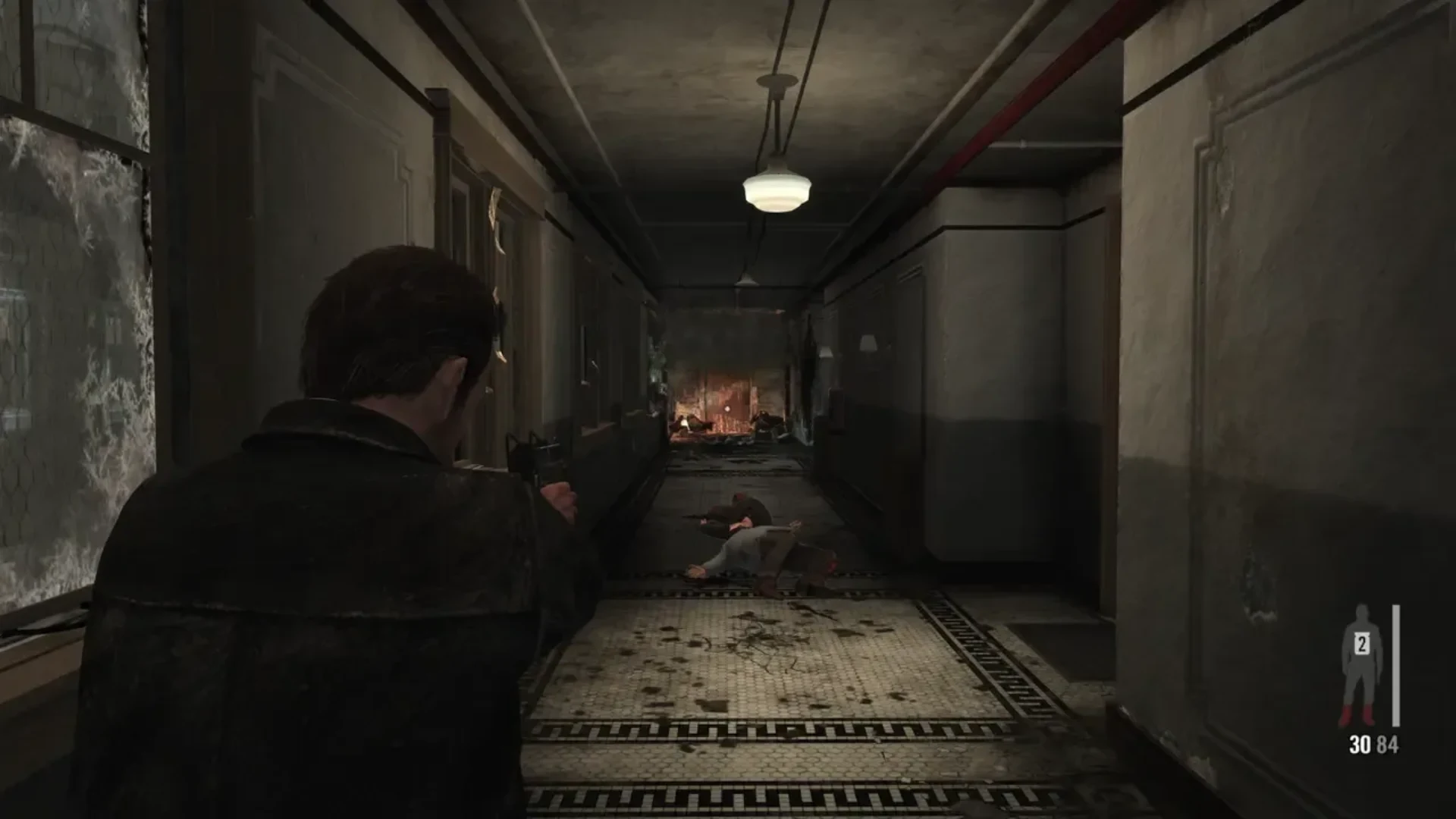 Max Payne aims a handgun down a damaged hallway in Max Payne 3
