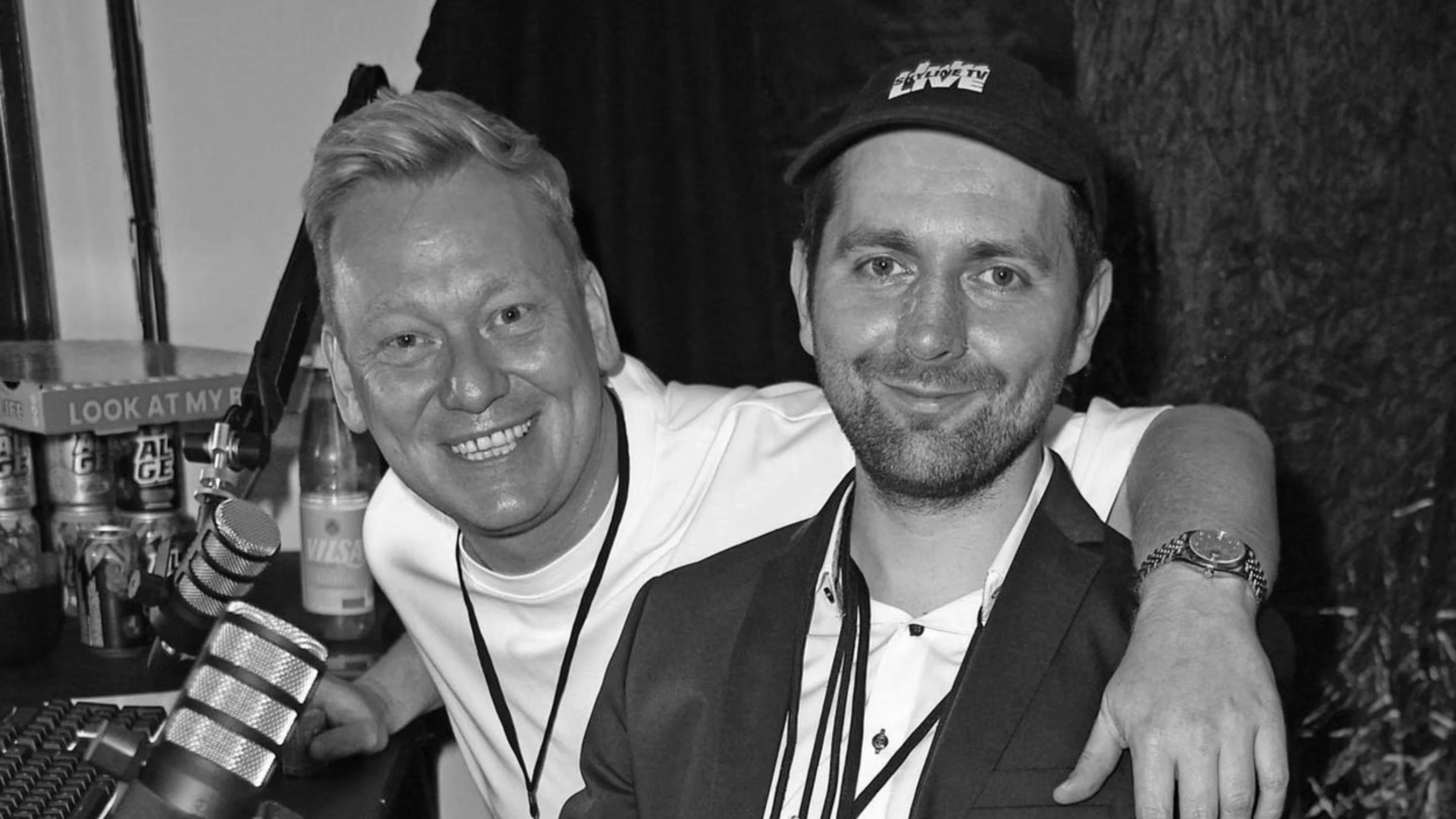Jens Knossi Knossalla and Adam Wolke, known as SkylineTV, smiling together in a black-and-white photograph with streaming microphones nearby.