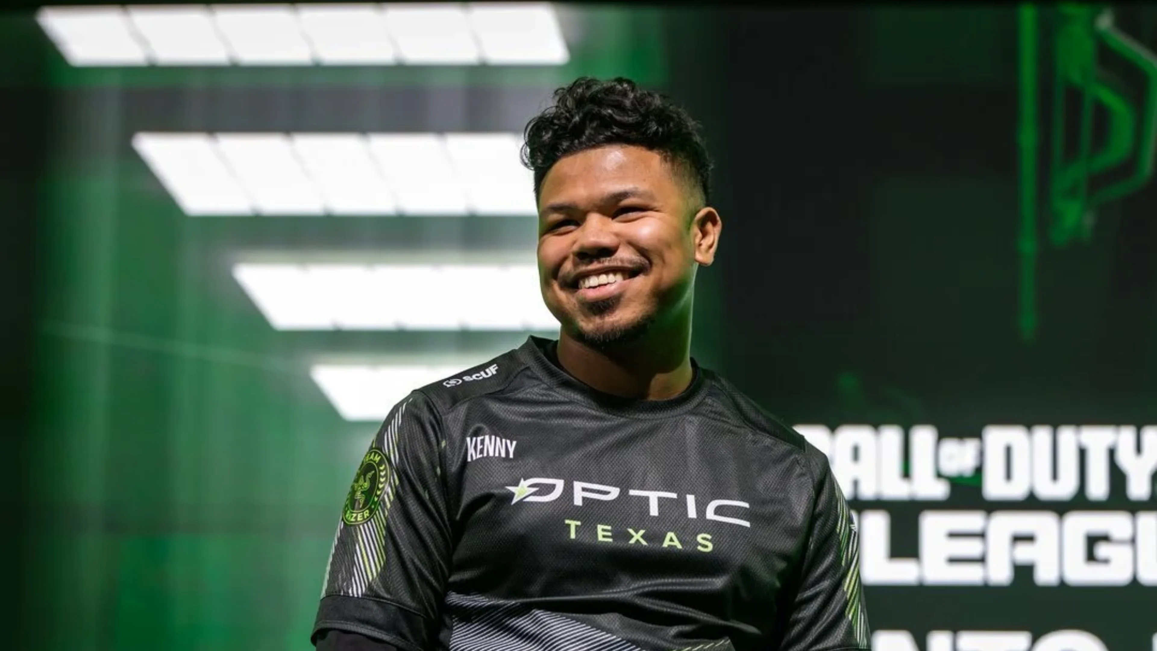 Kenny smiles in a black OpTic Texas jersey against a green-lit Call of Duty League backdrop.